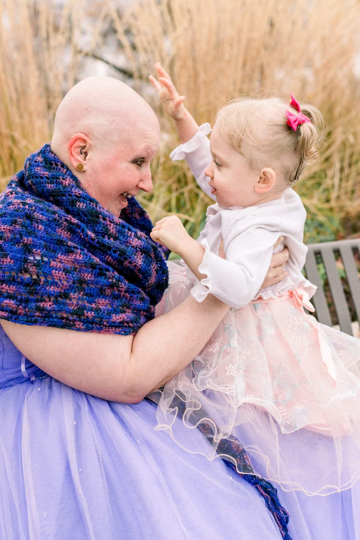 Cancer survivor picture sitting in a purple gown with her little girl in a little pink dress.