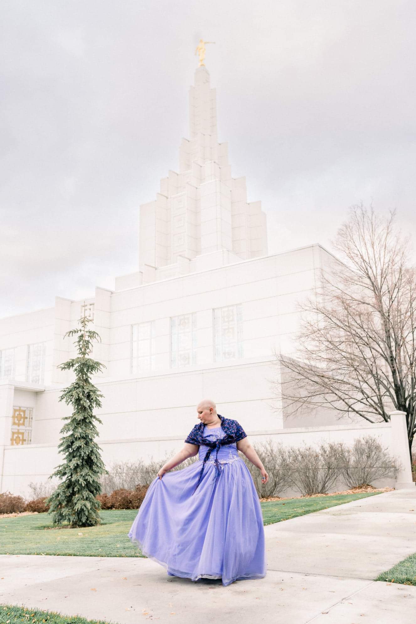 Cancer survivor from far away in a flowy purple gown with a large beautiful building behind her.